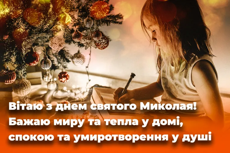 Дитина пише лист під ялинкою з прикрасами.