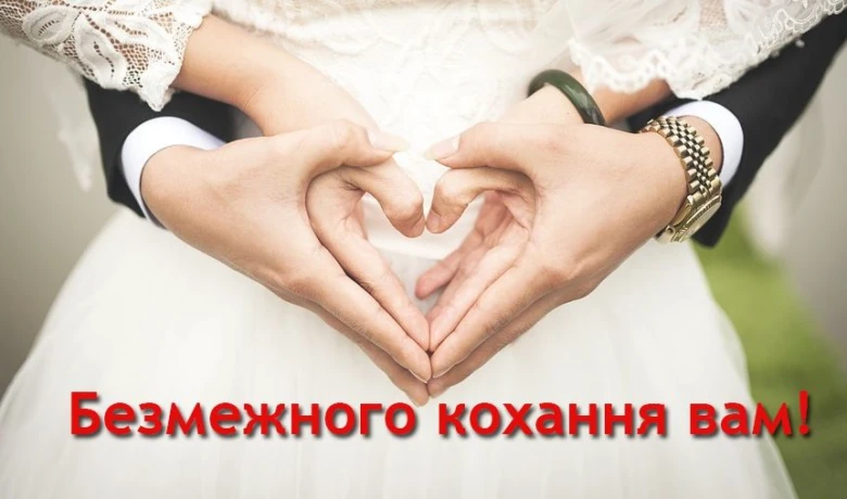 Руки утворюють серце на весільному фоні з українським привітанням.