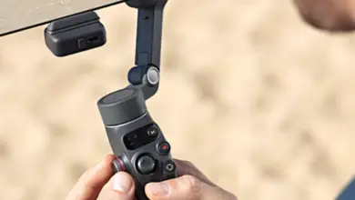 Людина тримає стабілізатор для смартфона від DJI на пляжі.
