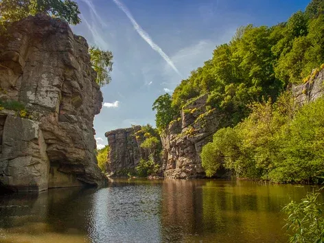 Скелясте річище з лісом на березах під блакитним небом