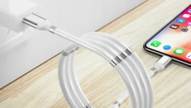 Білий iPhone заряджається через кабель на дерев'яній поверхні