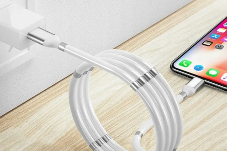 Білий iPhone заряджається через кабель на дерев'яній поверхні