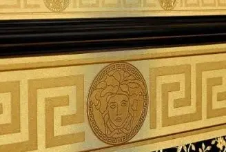 Деталь золотого шпалерного візерунку з грецькими мотивами та медезою на чорному фоні.